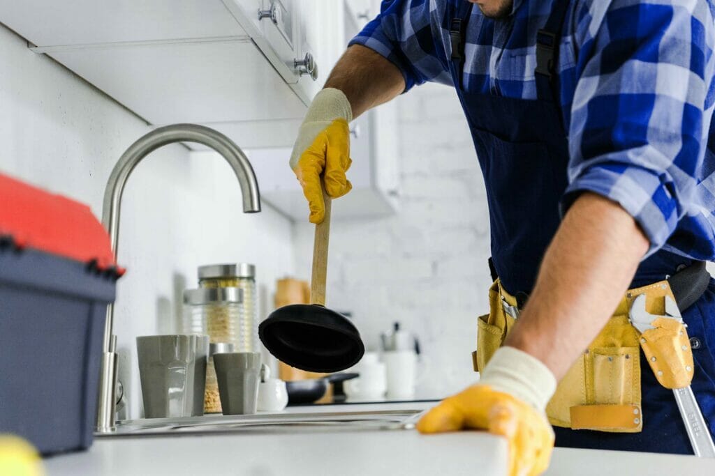 Cropped-View-Of-Repairman-Holding-Plunger-In-Kitch-Dnnctf2.Jpg